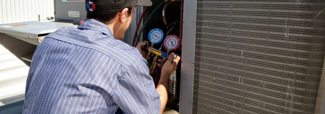 HVAC technician servicing a condenser unit in Huron